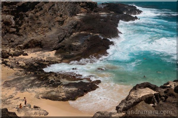 People enjoy the shallow waters of a rocky ocean beach