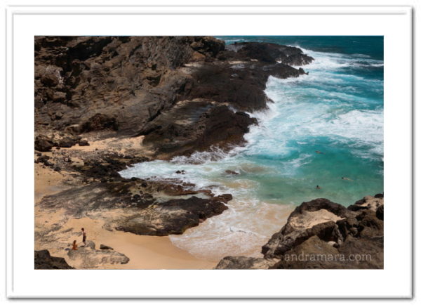 People enjoy the shallow waters of a rocky ocean beach